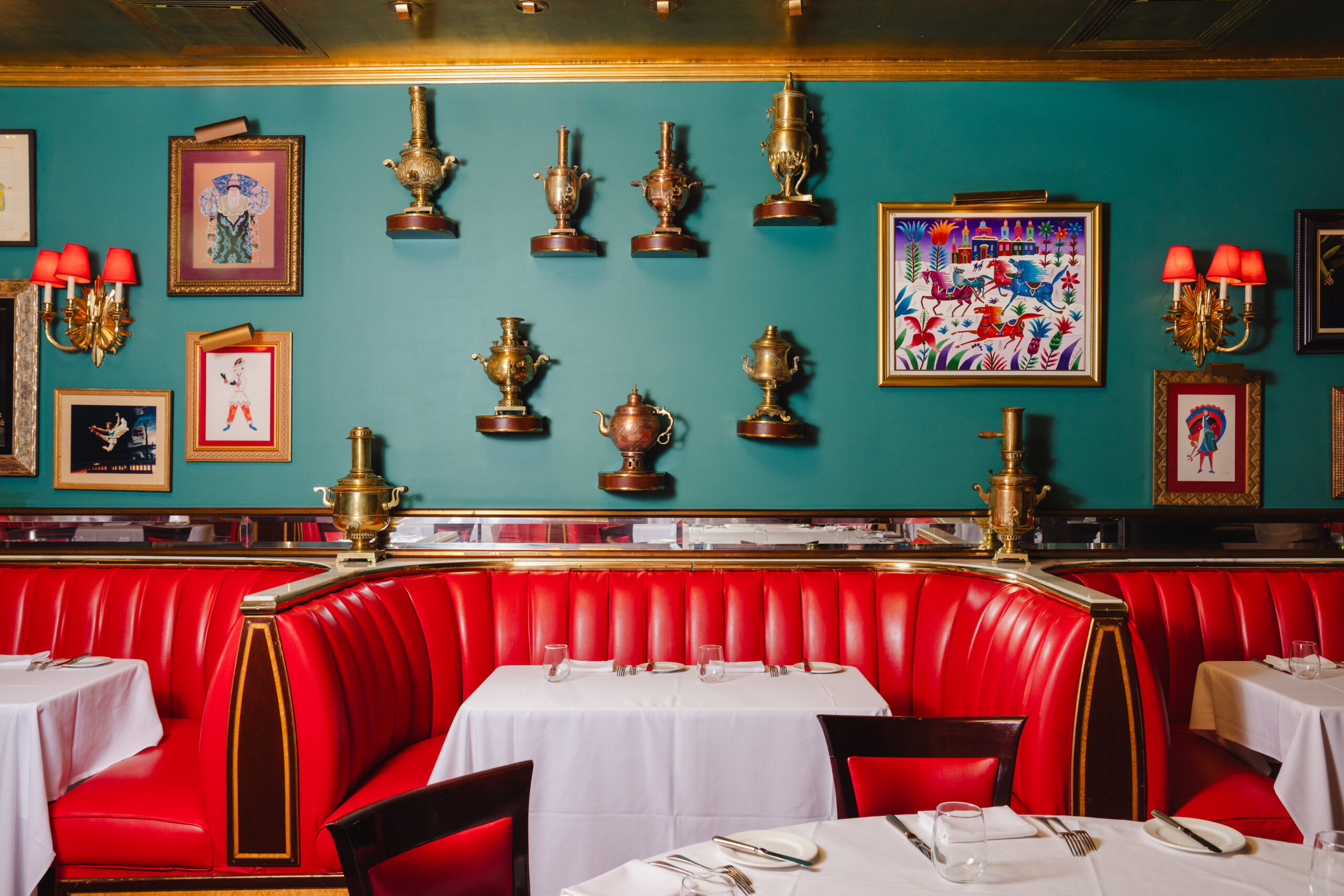 Red leather seating with decorative wall art and brass samovars