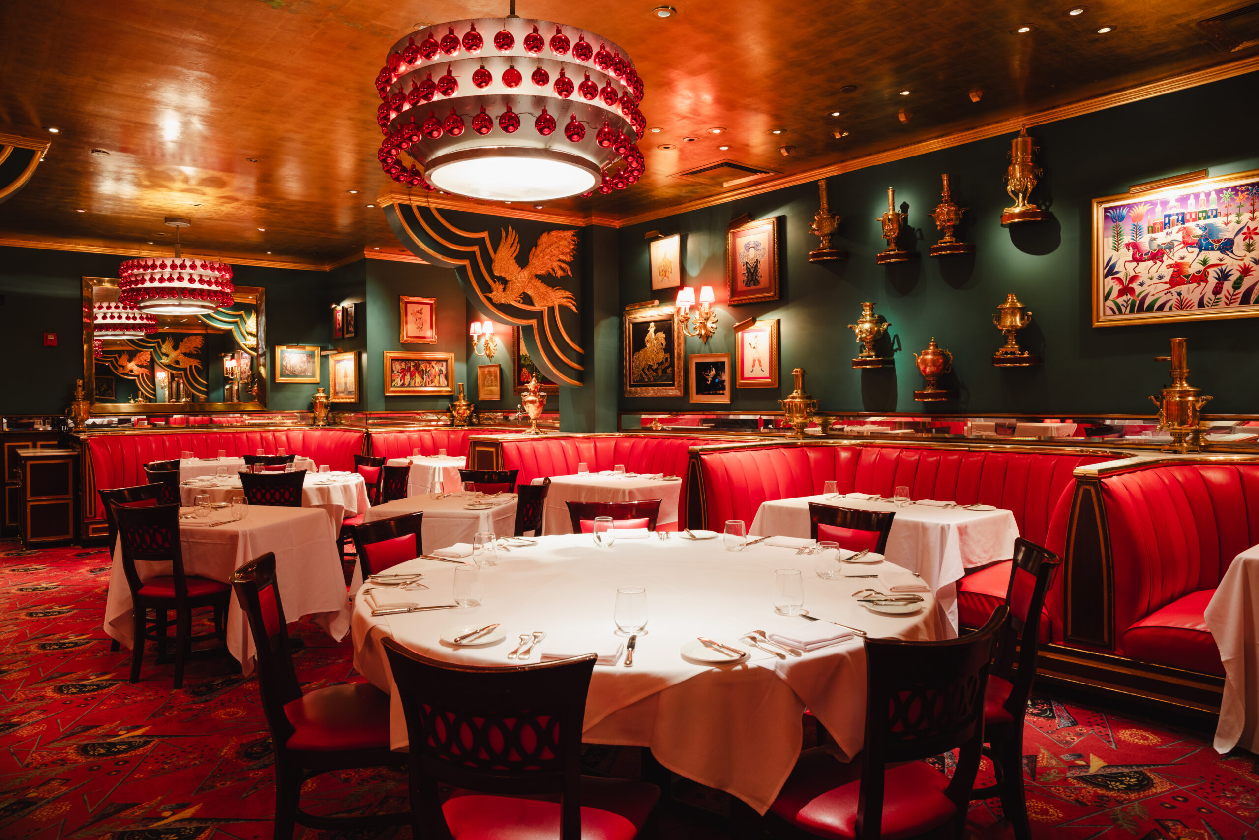 LannaApisukh_RussianTeaRoom-7214 Elegant dining room with red booths, round tables, and decorative wall art
